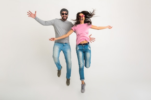 Hipster elegante pareja saltando aislado, mujer emocional muy sonriente y hombre vestido con jeans, activo y positivo, divirtiéndose juntos