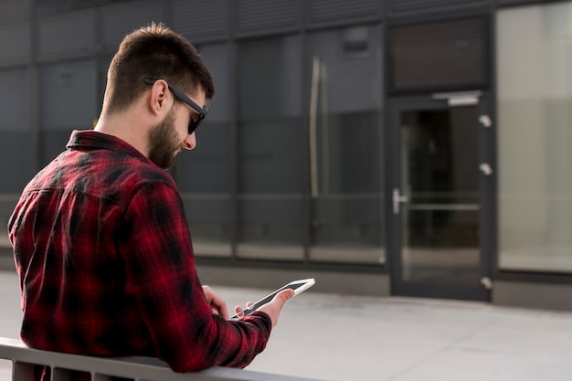 Foto gratuita hipster con gafas de sol con smartphone