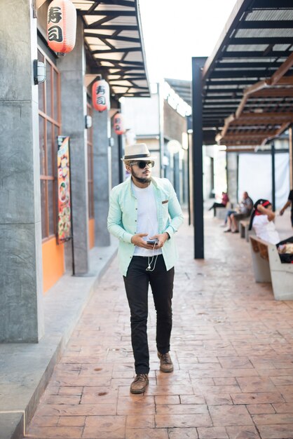 Hipster hombre escuchar música con su teléfono inteligente en la calle en la ciudad.