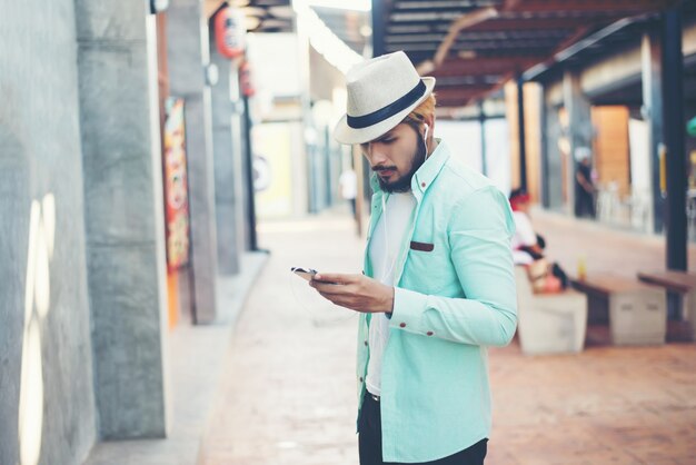 Hipster hombre escuchar música con su teléfono inteligente en la calle en la ciudad.