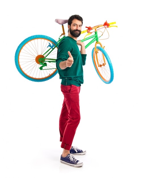 Hipster con el pulgar arriba sosteniendo una bici