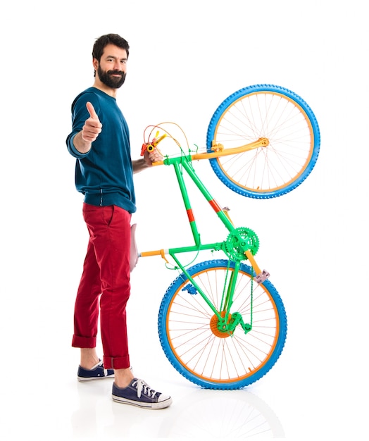 Hipster con el pulgar arriba sosteniendo una bici