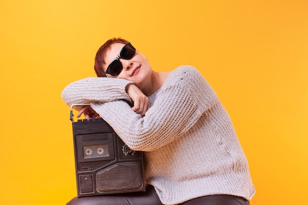 Hipster senior mujer descansando sobre un reproductor de cassette vintage