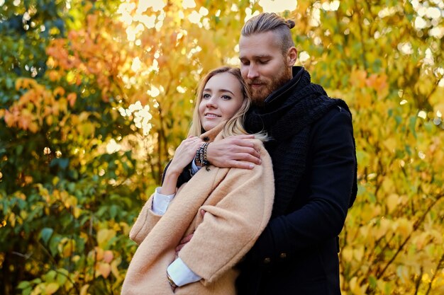 Historia de amor de otoño. Hombre atractivo pelirrojo abraza a linda mujer rubia en el fondo de la naturaleza salvaje de otoño.