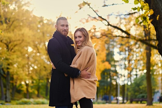 Historia de amor de otoño. Hombre atractivo pelirrojo abraza a linda mujer rubia en el fondo de la naturaleza salvaje de otoño.