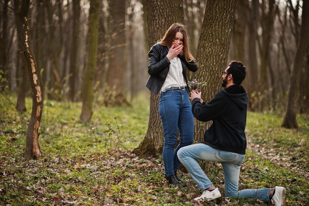 Historia de amor de una pareja multirracial genial en el bosque de primavera Propuesta de matrimonio de un hombre árabe a una chica europea