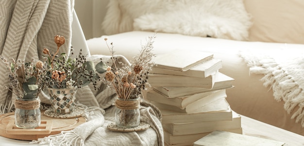 Hogar acogedor interior de la habitación con libros y flores secas en un jarrón.