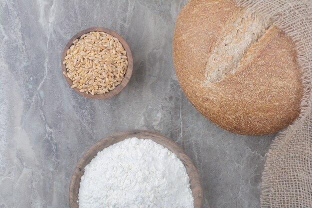 Una hogaza de pan blanco con granos de avena y harina sobre la superficie de mármol