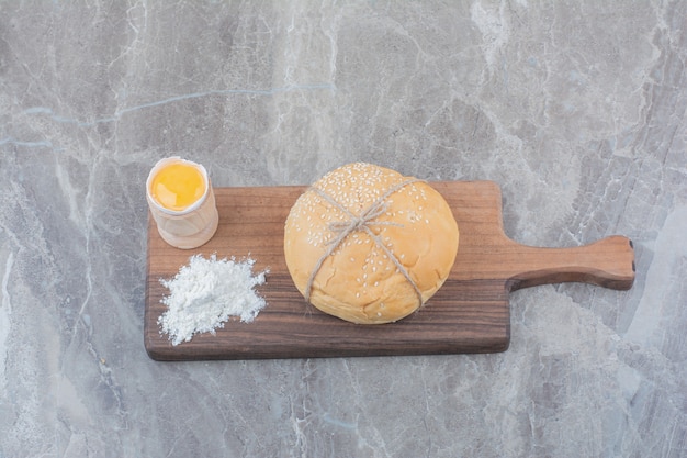 Foto gratuita una hogaza de pan blanco con yema y harina sobre tabla de madera