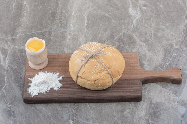Una hogaza de pan blanco con yema y harina sobre tabla de madera