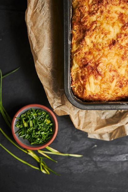 Hogaza de pan de queso con mantequilla de hierbas en una placa de madera con hierbas