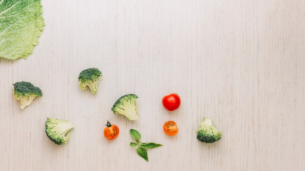 Hoja de col brócoli; Albahaca y tomates cherry en superficie de madera