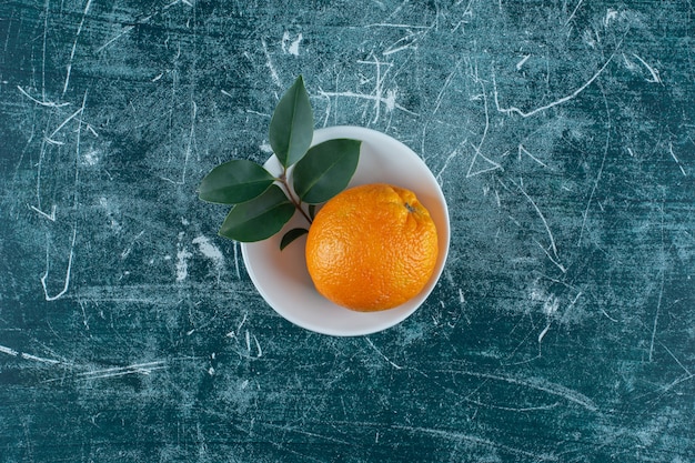 Hoja y mandarina en un tazón, sobre el fondo de mármol. Foto de alta calidad