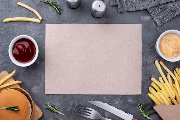 Foto gratuita hoja de papel al lado de hamburguesas y papas fritas