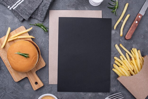 Hoja de papel en blanco al lado de hamburguesas y papas fritas