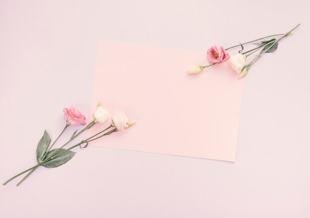 Hoja de papel en blanco con flores brillantes en la mesa