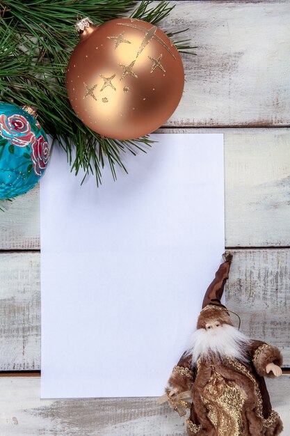 La hoja de papel en blanco sobre la mesa de madera con adornos navideños.