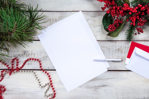 Foto gratuita hoja de papel en blanco sobre la mesa de madera con un bolígrafo y adornos navideños.