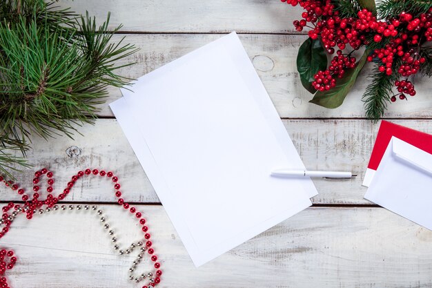 hoja de papel en blanco sobre la mesa de madera con un bolígrafo y adornos navideños.