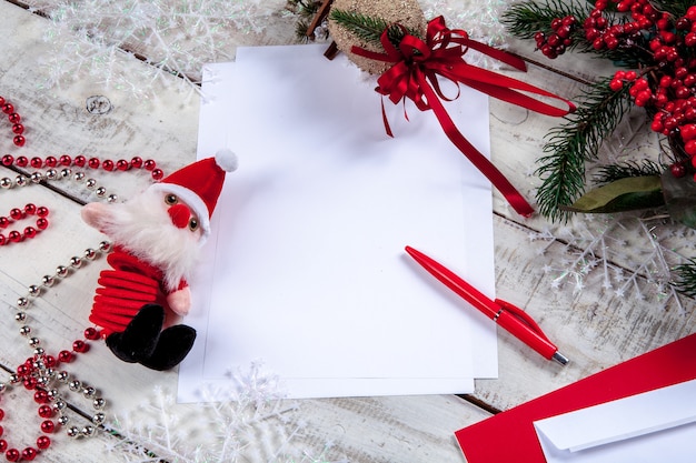 hoja de papel en blanco sobre la mesa de madera con una pluma y Santa.