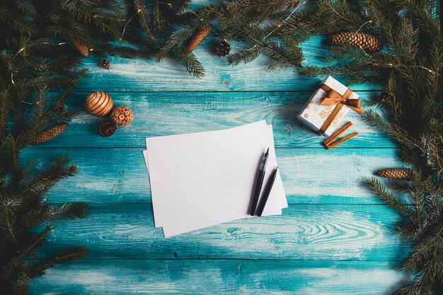 Hoja de papel en blanco en una tabla de madera azul con artículos de Navidad. Concepto de Navidad.