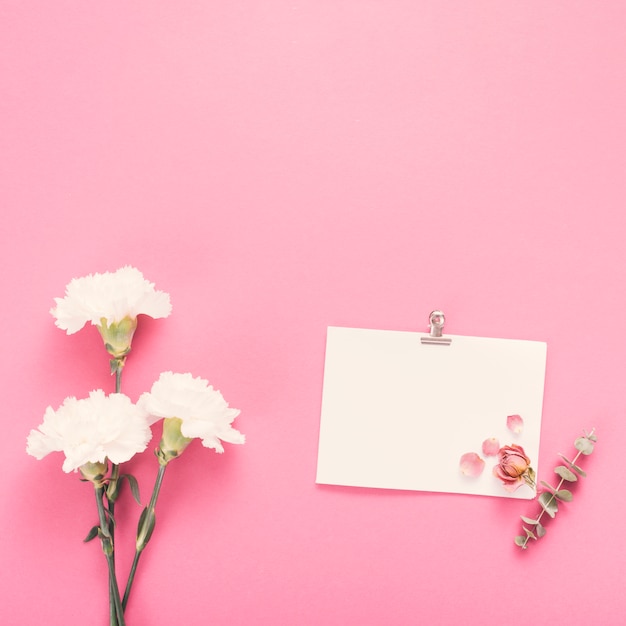 Foto gratuita hoja de papel pequeña con flores blancas en mesa.