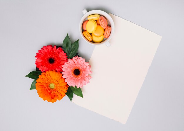 Hoja de papel con pequeñas galletas y flores en la mesa