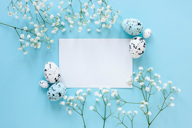 Hoja de papel sobre la mesa junto a huevos pintados y flores