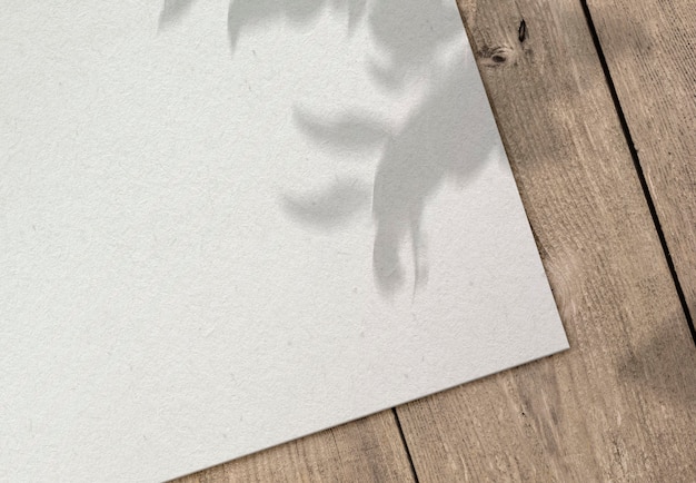 Foto gratuita hoja de papel en superficie de madera con sombra