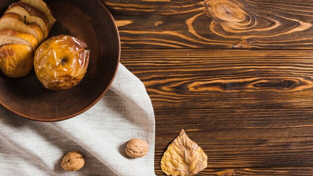 Hoja seca y nuez cerca de manzana al horno y paño