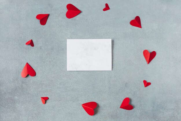 Hoja entre los símbolos de papel rojo del corazón en forma de círculo