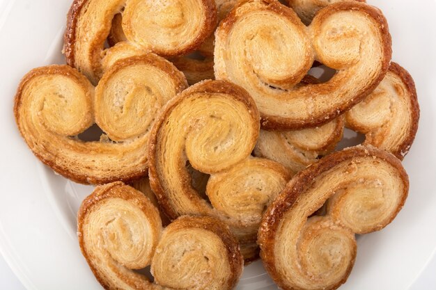 Hojaldre Palmier en placa aislado sobre fondo blanco.