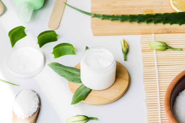 Hojas de aloe vera con un tarro de crema de belleza