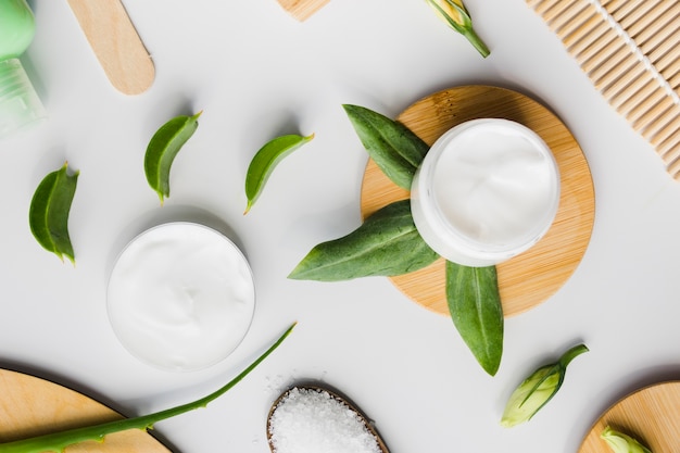 Hojas de aloe vera con un tarro de crema de belleza