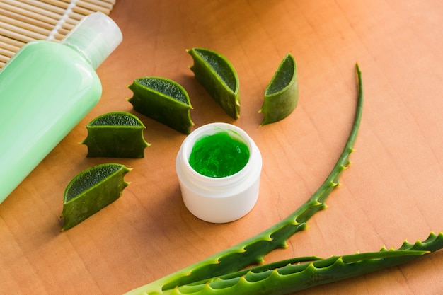 Hojas de aloe vera con un tarro de crema de belleza