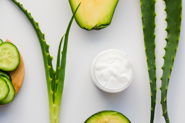 Hojas de aloe vera con un tarro de crema de belleza