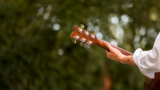 Hojas borrosas y hombre tocando la guitarra desde detrás de tiro