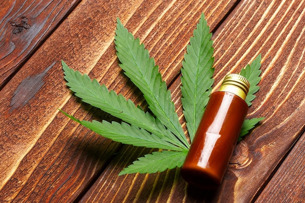 Hojas de cannabis y aceite sobre fondo de madera