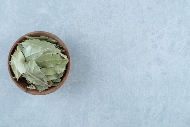 Foto gratuita hojas de laurel secas verdes en una taza de madera. foto de alta calidad