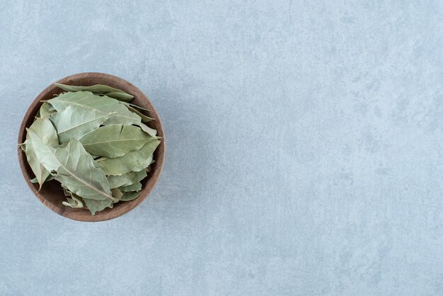 Hojas de laurel secas verdes en una taza de madera. Foto de alta calidad