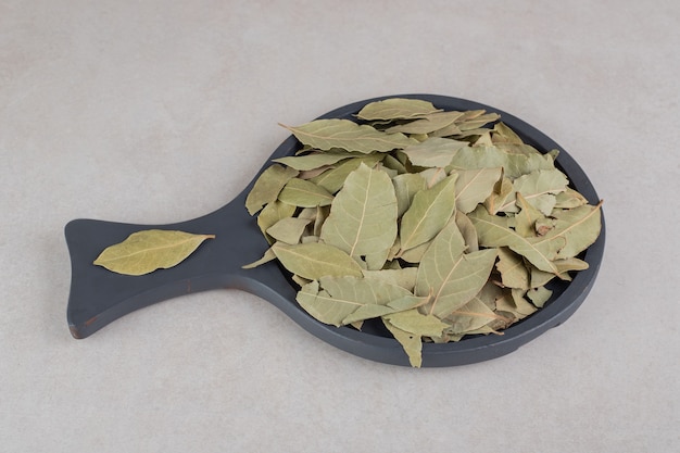 Foto gratuita hojas de laurel verde secas en un plato de madera.