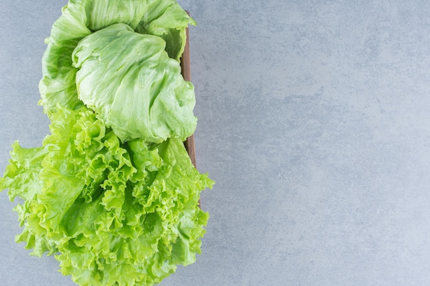 Hojas de lechuga orgánica fresca en un tazón sobre fondo gris.