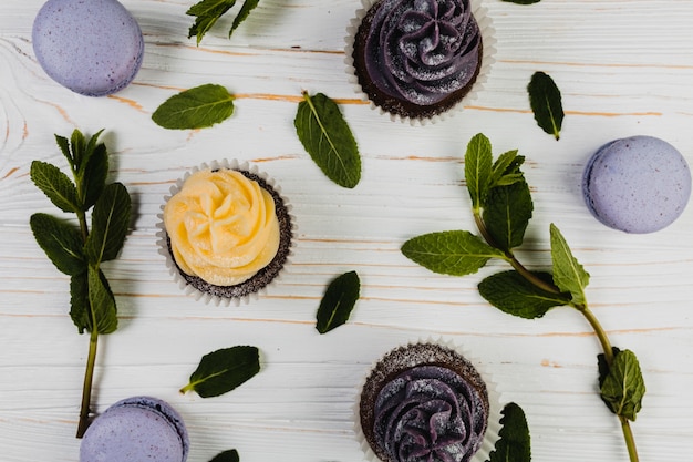 Foto gratuita hojas en medio de cupcakes y macarrones