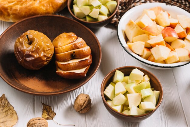 Hojas y nueces cerca de manzanas cocidas y cortadas