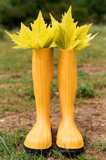 Hojas de otoño en botas de lluvia