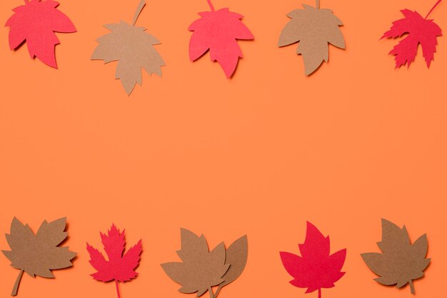 Hojas de otoño de papel plano sobre fondo naranja con espacio de copia