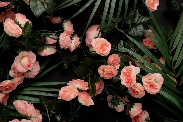 Hojas de palmera con fondo de flores rosas