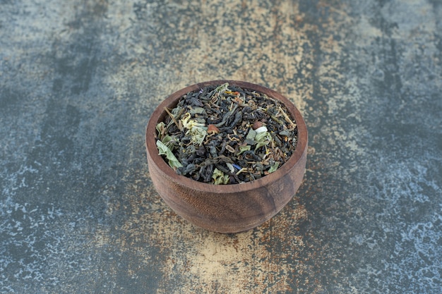 Hojas de té de hierbas en un tazón de madera.