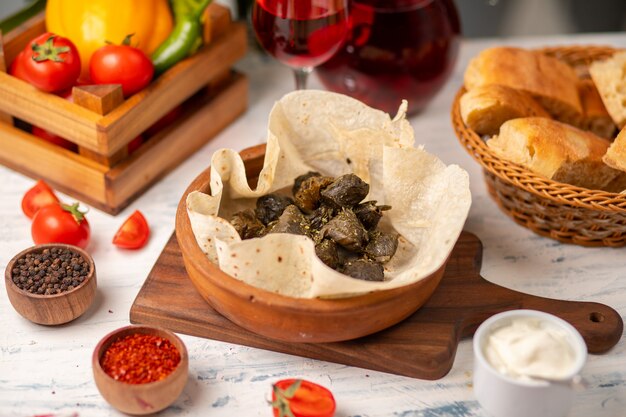 Hojas de uva verdes rellenas de carne, arroz, hierbas, cebolla y cocidas en aceite de oliva, servidas con lavash y pan. Dolmasi arpa, yaprak sarmasi