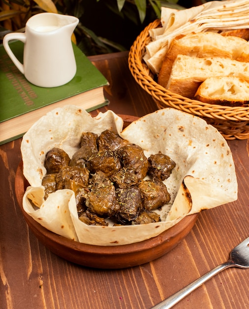 Hojas de uva verdes rellenas de carne, arroz, hierbas, cebolla y cocidas en aceite de oliva, servidas con lavash y pan. Dolmasi arpa, yaprak sarmasi